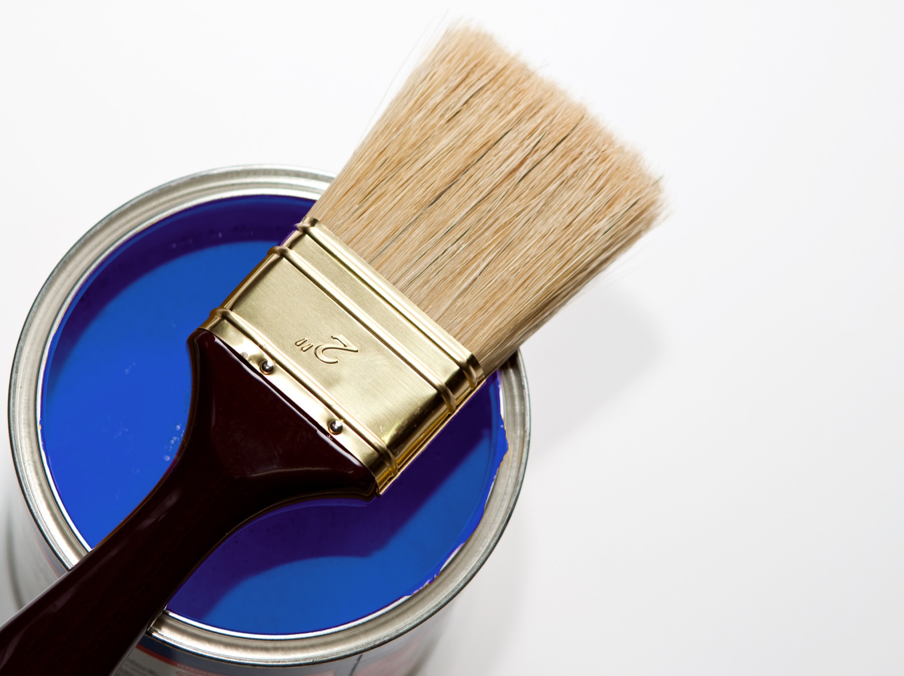 Open tin of ultramarine blue paint with a decorator's brush resting on the rim