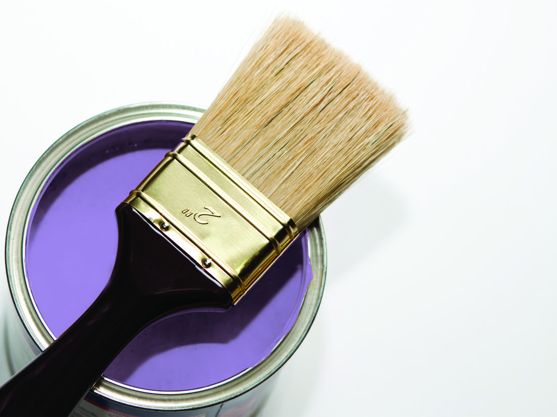 Tin of ultramarine violet paint with a brush laid across the opening